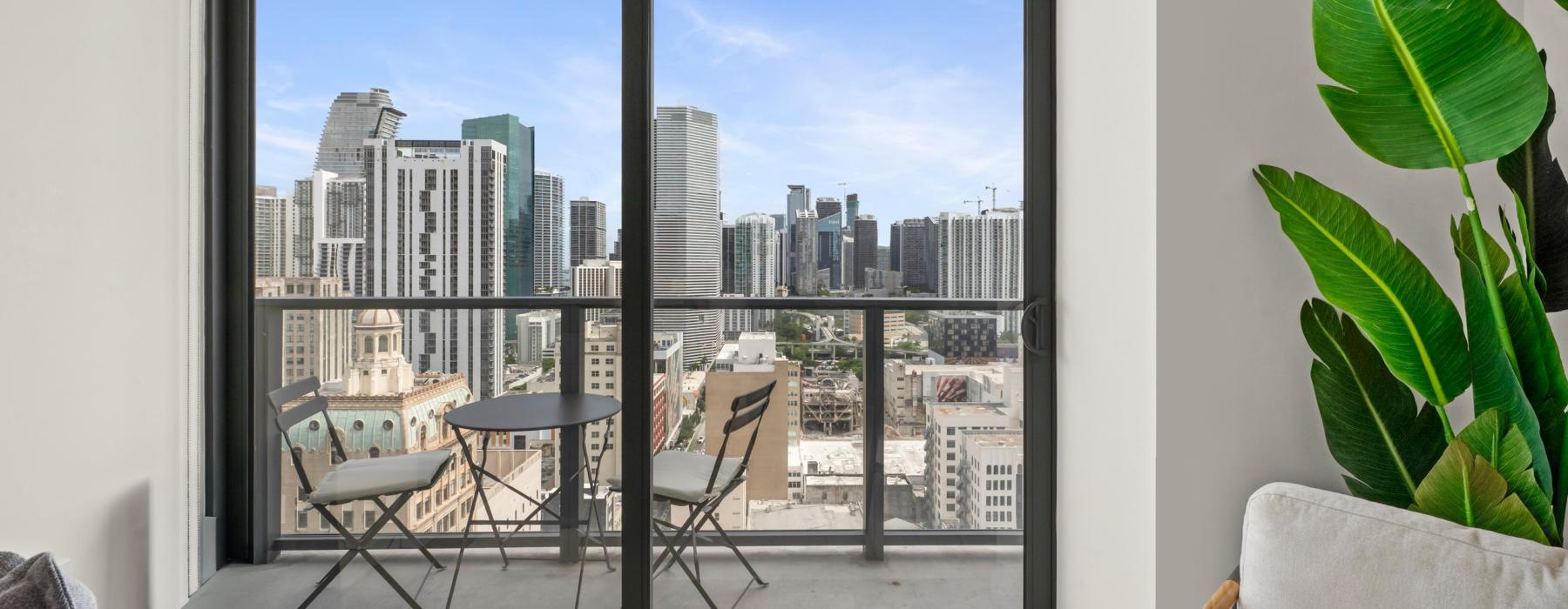 a room with a table and chairs and a window with a view of a city