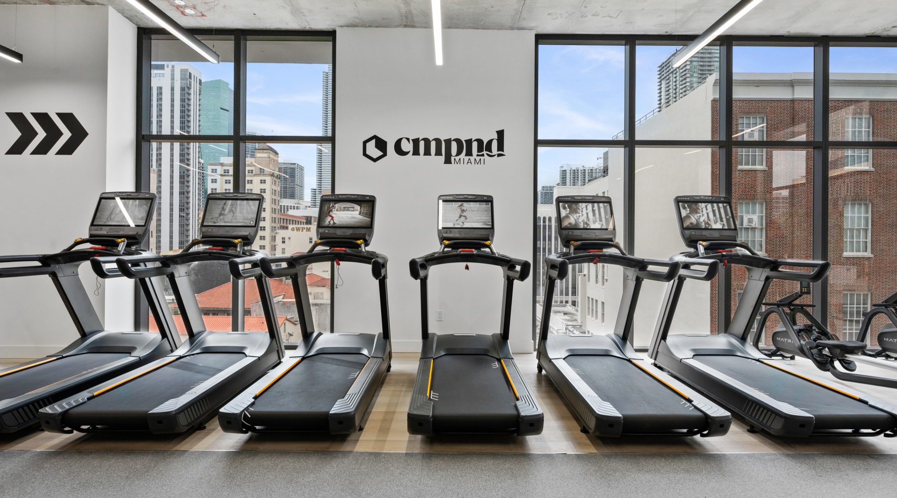 CMPND Miami fitness center with Matrix treadmills and floor-to-ceiling windows overlooking downtown Miami