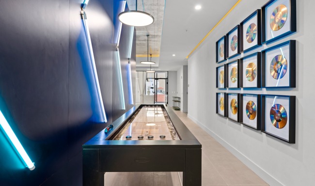 Shuffleboard game room at CMPND Miami with neon accent wall and framed gold record wall art