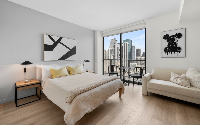 Furnished bedroom at CMPND Miami with king bed, balcony, and downtown Miami skyline views