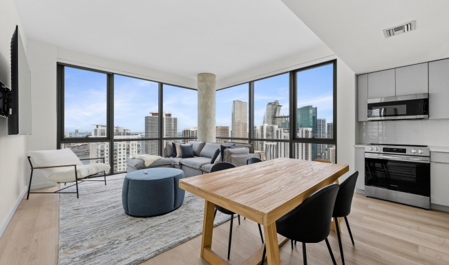 Luxury CMPND Miami apartment living and dining area with floor-to-ceiling windows, downtown Miami skyline views, and a stainless steel kitchen