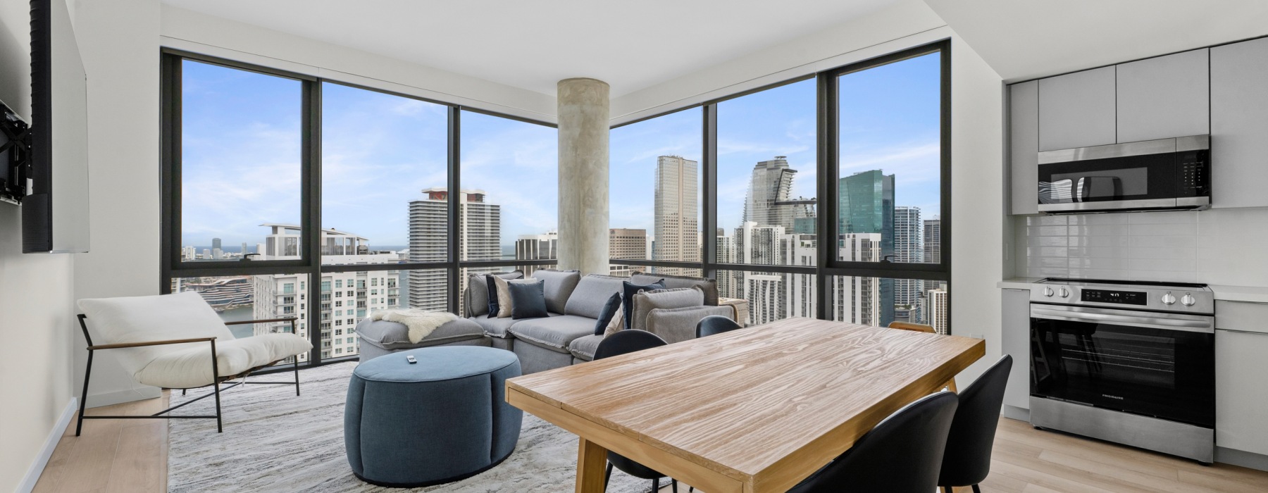 Luxury CMPND Miami apartment living and dining area with floor-to-ceiling windows, downtown Miami skyline views, and a stainless steel kitchen